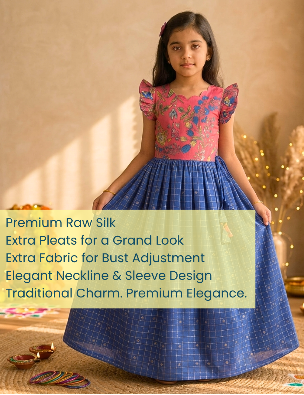 A young girl modeling a traditional Indian dress made of blue raw silk with a pink floral embroidered bodice and puffed sleeves, set against a warm beige background with decorative bokeh lights.