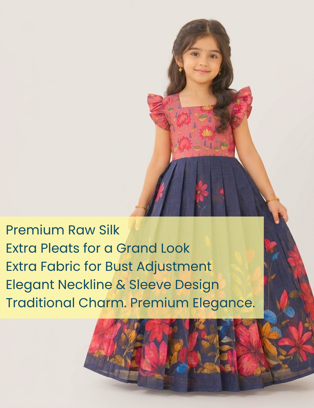 A young girl modeling a traditional Indian dress made of dark navy blue raw silk with a pink floral bodice and a voluminous skirt with pink and red floral patterns. A text overlay on the left highlights the dress features.